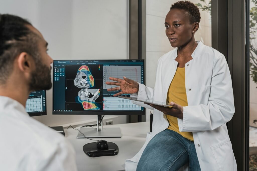 Two clinicians discussing diagnostic imaging displayed on computer monitors