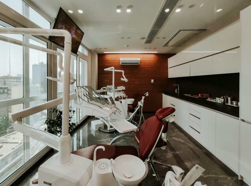Modern dental surgery with treatment chairs beside floor to ceiling windows overlooking a city skyline