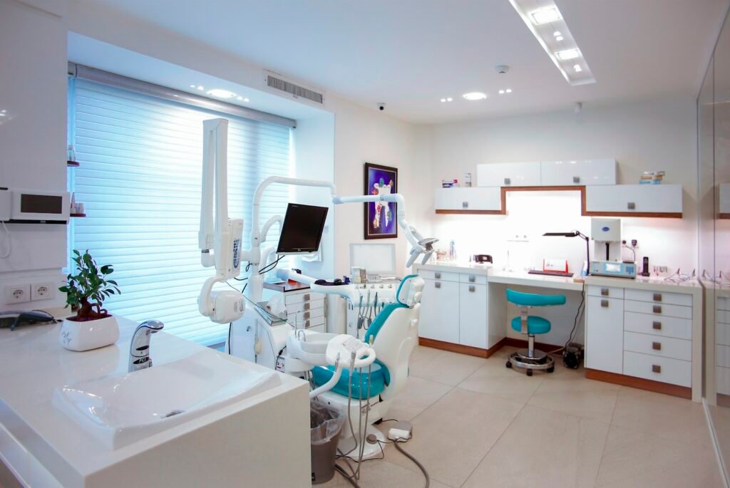 Bright, clean dental treatment room with chair, overhead light and monitor
