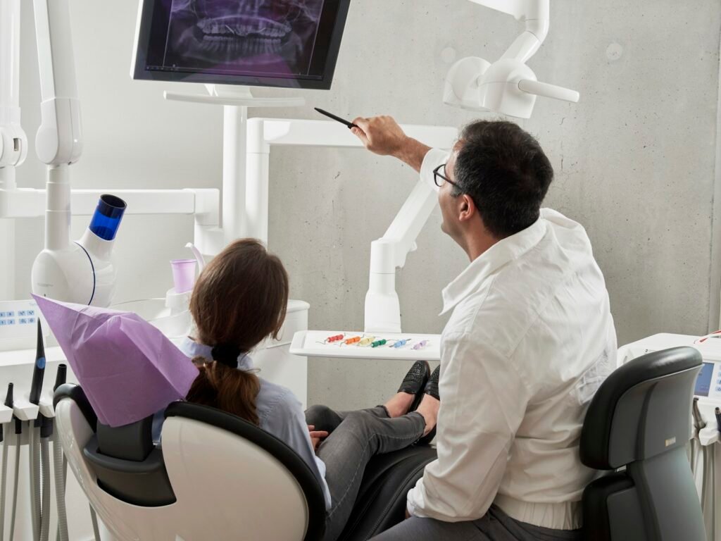 Dentist reviewing a dental X-ray on screen with a patient in the treatment chair