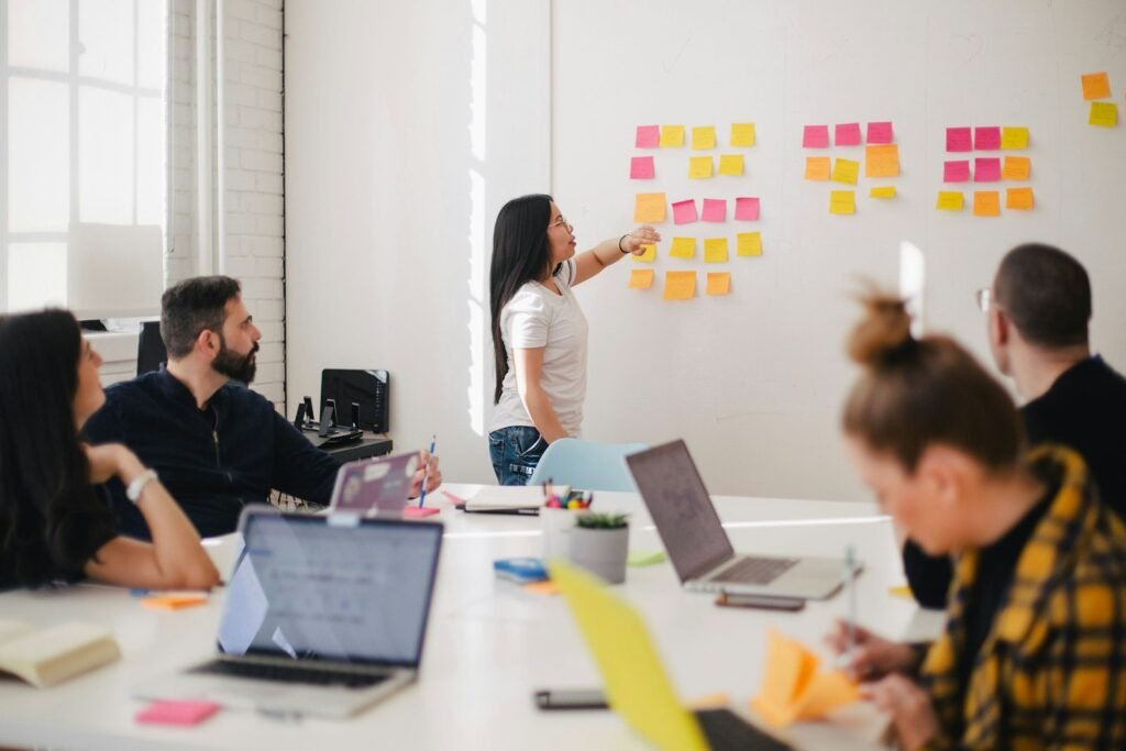Marketing team planning session with colleagues around a table and sticky notes on the wall